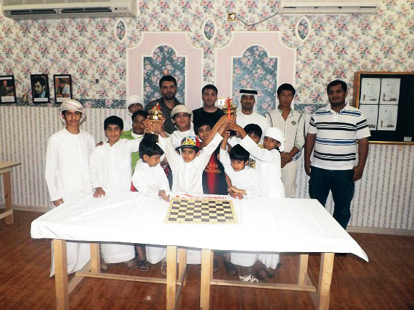 Haitham Alkindi raising his trophy with fellow competitors at a Fujairah Chess Club tournament prize-giving, 2013